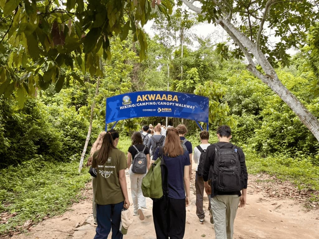 Travelers walking under the Akwaaba gateway at a canopy walkway in Ghana